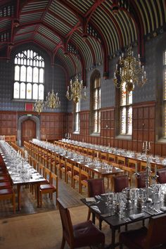 an empty dining hall with long tables and chandeliers