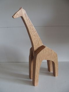 a wooden toy giraffe standing upright on a white surface with its head turned to the side