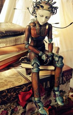 a wooden statue sitting on top of a pile of books