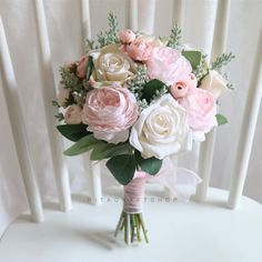 a bouquet of pink and white flowers sitting on top of a chair