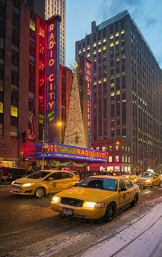 a city street filled with lots of traffic and tall buildings covered in snow at night