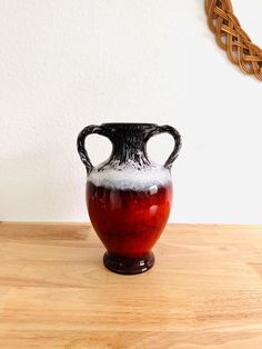 a black and white vase sitting on top of a wooden table