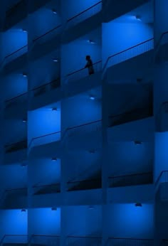 a person walking up the stairs in an apartment building at night with blue lights on