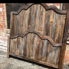 an old wooden headboard sitting in front of a brick wall