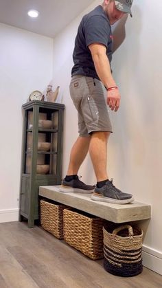 a man standing on top of a bench next to baskets and a wall mounted clock