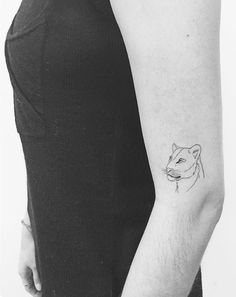 a cat tattoo on the arm of a woman's left arm, which is black and white