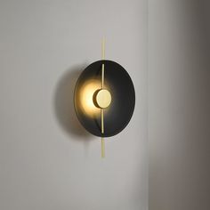 a black and gold light hanging from the side of a wall next to a white wall