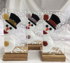 two glass snowmen on wooden bases with white background