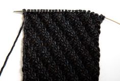 a close up of a black knitted piece of cloth with a needle in it