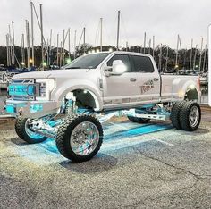 a large white truck parked in a parking lot with lots of boats and lights behind it