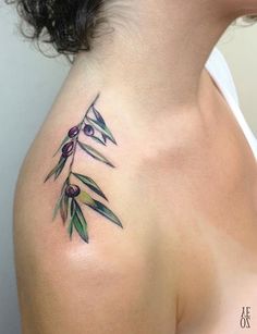 an olive branch tattoo on the back of a woman's shoulder