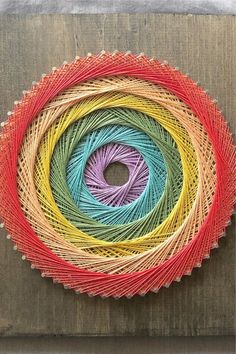 several colors of yarn are arranged in a circle on a wooden surface with a metal frame