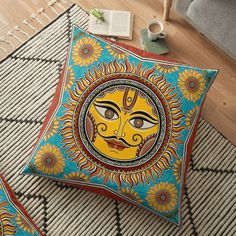 decorative sun face on blue and yellow floor pillow with coffee cup next to it in living room