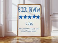 a book review sign sitting on top of a hard wood floor next to a white wall