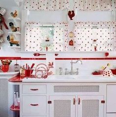 a white kitchen with red accents and polka dots on the wall above the countertop