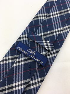 "For the man who loves plaid, Ed's Neckties offers this 100% silk mens plain necktie. Features a navy blue background with blue, gray and red plaid pattern. Available as a extra long tie. Handmade from 100% silk, this special collection features a .75\" Eds Neckties logo at the bottom right front corner of every tie and a larger logo located on the tipping (Back of the tie). The label features the collection name (Nathaniel Alexandria) Named after my son Nathaniel and my daughter Alexandria. Exp Classic Plaid Suit And Tie Accessories For Office, Classic Plaid Business Suit And Tie Accessories, Plaid Suit And Tie Accessories For Business, Classic Plaid Ties For Formal Occasions, Classic Ties For Father's Day, Classic Plaid Standard Tie, Fitted Plaid Ties, Make A Tie, White Goth