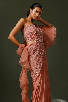 Pink asymmetric sleeves one shoulder saree gown encrusted with sequins, cutbeads, feather work and organza ruffled power sleeve on one side extending into ruffled drape.
Components: 1
Pattern: Embroidery
Type Of Work: Thread Work, Cut Dana, Sequin
Neckline: One Shoulder
Sleeve Type: Asymmetric Sleeves
Fabric: Crepe: Bottom , Net: Drape and Organza: Sleeves
Color: Pink
Other Details: 
Padded saree gown
Occasion: Cocktail - Aza Fashions Draped Saree Gown, Embellished Saree, Embroidery Thread Work, Saree Gowns, Set Saree, Saree Gown, Organza Sleeves, Drape Saree, Sharara Set