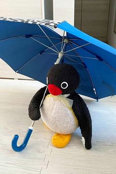 a stuffed penguin holding an umbrella on the ground