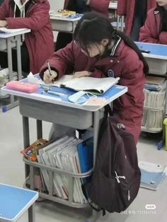 a group of people sitting at desks in a classroom with books and papers on them