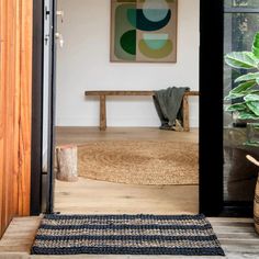 an entryway with a rug, potted plant and wooden bench in the background