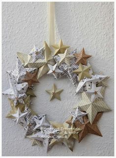 an origami wreath made out of newspaper stars on a white wall with a ribbon