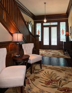 two white chairs sitting in front of a wooden banister next to a stair case