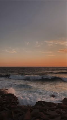 the sun is setting over the ocean with waves