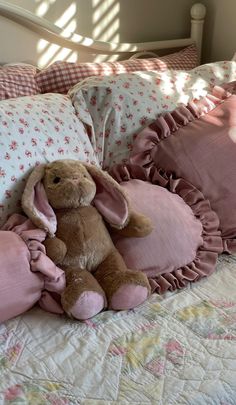 a stuffed rabbit sitting on top of a bed next to pillows and pillowcases