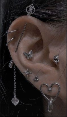 an ear with several piercings attached to it's sides, including a heart and cross