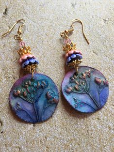 These Ceramic Earrings are made with charms made by an artisan.  The earrings are accented with ceramic and metal flower bead caps and Swarovski crystals Artistic Purple Dangle Earrings, Purple Artisan Earrings With Ear Wire, Artisan Purple Earrings With Ear Wire, Artisan Purple Drop Earrings, Bohemian Hand Painted Purple Earrings, Purple Hand Painted Bohemian Earrings, Artistic Handmade Dangle Earrings, Unique Dangle Flower Earrings, Unique Dangle Flower Earrings With Ear Wire