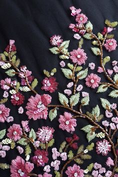 an embroidered fabric with pink flowers and green leaves on black background, close - up