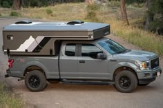 a truck with a camper attached to it's bed parked on the side of a road