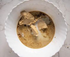 a white bowl filled with food sitting on top of a marble counter next to a knife