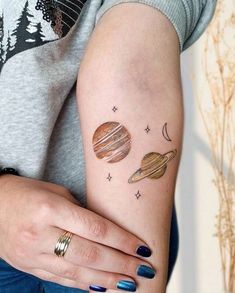 a woman's arm with tattoos on it and planets painted on the back of her arm