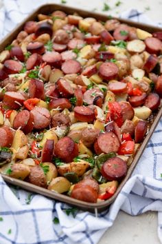 a pan filled with potatoes and sausages on top of a blue and white towel