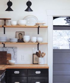 a kitchen with black cabinets and white dishes on the shelves above it is an image of a man's face