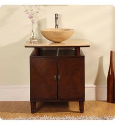 a bathroom sink sitting on top of a wooden cabinet next to a vase with flowers