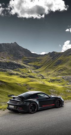 a black sports car parked on the side of a road in front of some mountains