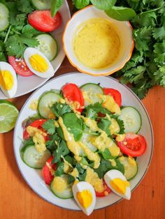 a salad with eggs, tomatoes and cucumbers on a plate next to other vegetables