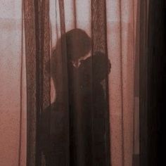 the shadow of a person standing in front of a curtain