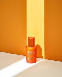 an orange bottle sitting on top of a white table next to a yellow and orange wall