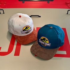 Greet new visitors to Isla Nublar at the helipad, or care for the extraordinary creatures of Jurassic Park wearing these stylish ball caps, exquisite recreations of the caps worn by staff members of the park. These hats feature a high profile twill crown and a contrasting faux suede polyester microfiber brim. The Jurassic Park logo is embroidered onto the front of the hat, and snapback straps make the hat adjustable from approximately 6 7/8 to 7 5/8. Also see the pink Jeep driver polos and belts Isla Nublar, Jurassic Park Logo, Pink Jeep, Ball Caps, Poly Bags, Jurassic Park, Ball Cap, Embroidery Logo, Trucker Cap