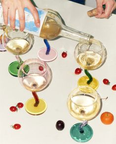 a person pours wine into glasses with cherries