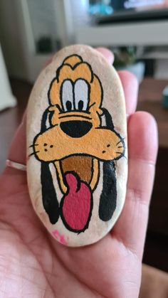 a hand holding a rock with a cartoon dog on it's face and tongue sticking out