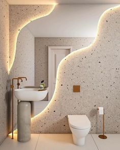 a bathroom with a white toilet sitting next to a sink under a light on the wall