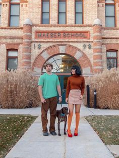 a man and woman standing in front of a brick building with a dog on leash