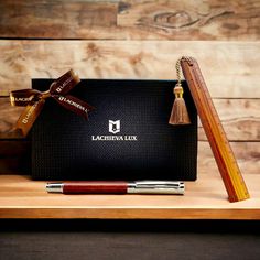 a wooden pen sitting on top of a desk next to a black box with a tassel