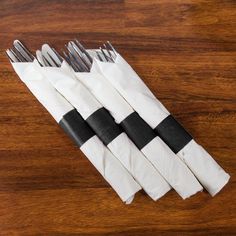 four forks are wrapped in brown paper on a wooden table