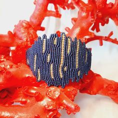 a blue and gold beaded bracelet sitting on top of red corals in the ocean