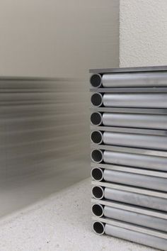 a stack of stainless steel tubes sitting on top of a white counter next to a wall